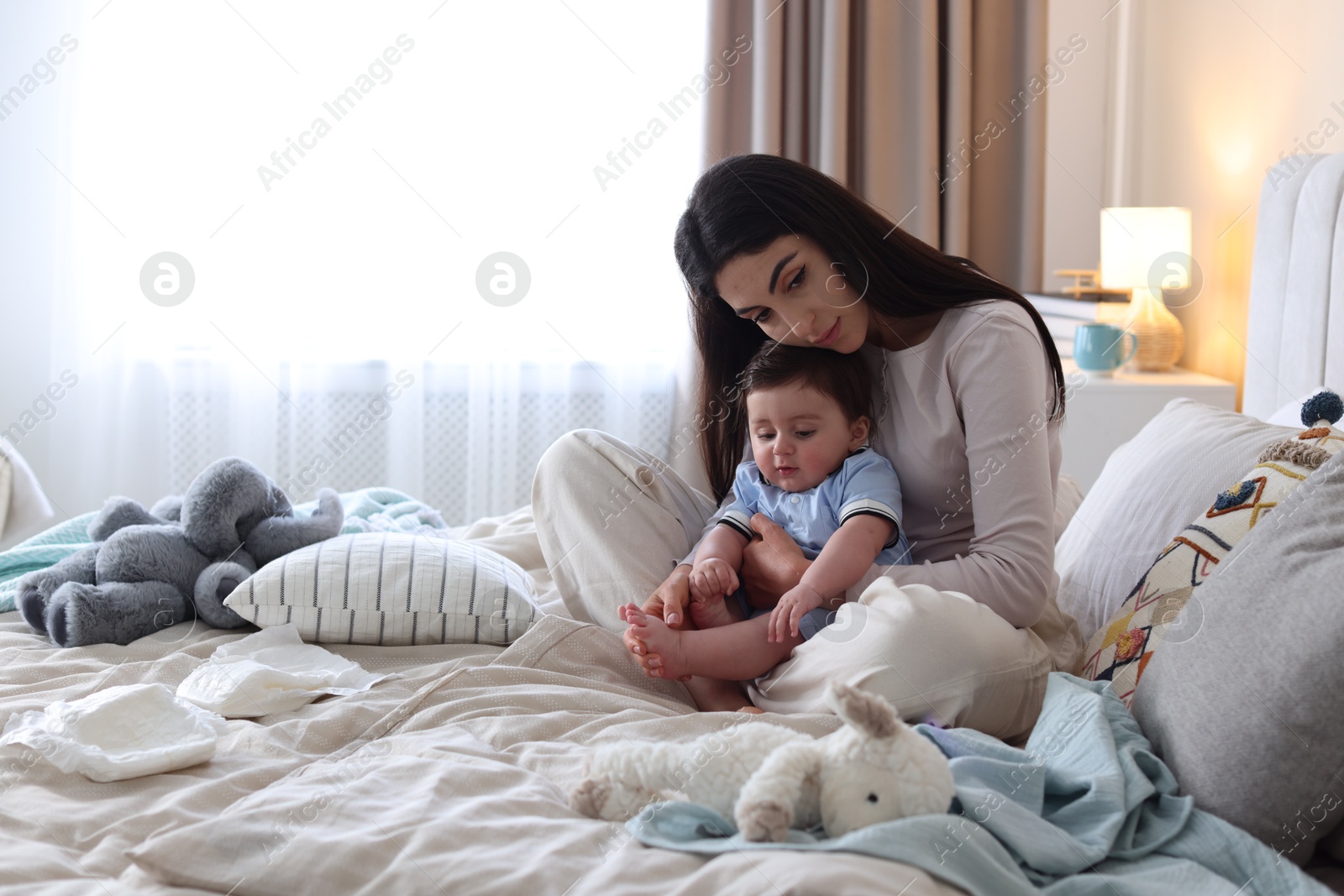 Woman suffering from postpartum depression with her little baby on bed at home. Space for text Photo of Woman suffering from postpartum depression with her little baby on bed at home. Space for text