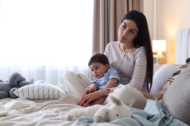 Photo of Woman suffering from postpartum depression with her little baby on bed at home. Space for text