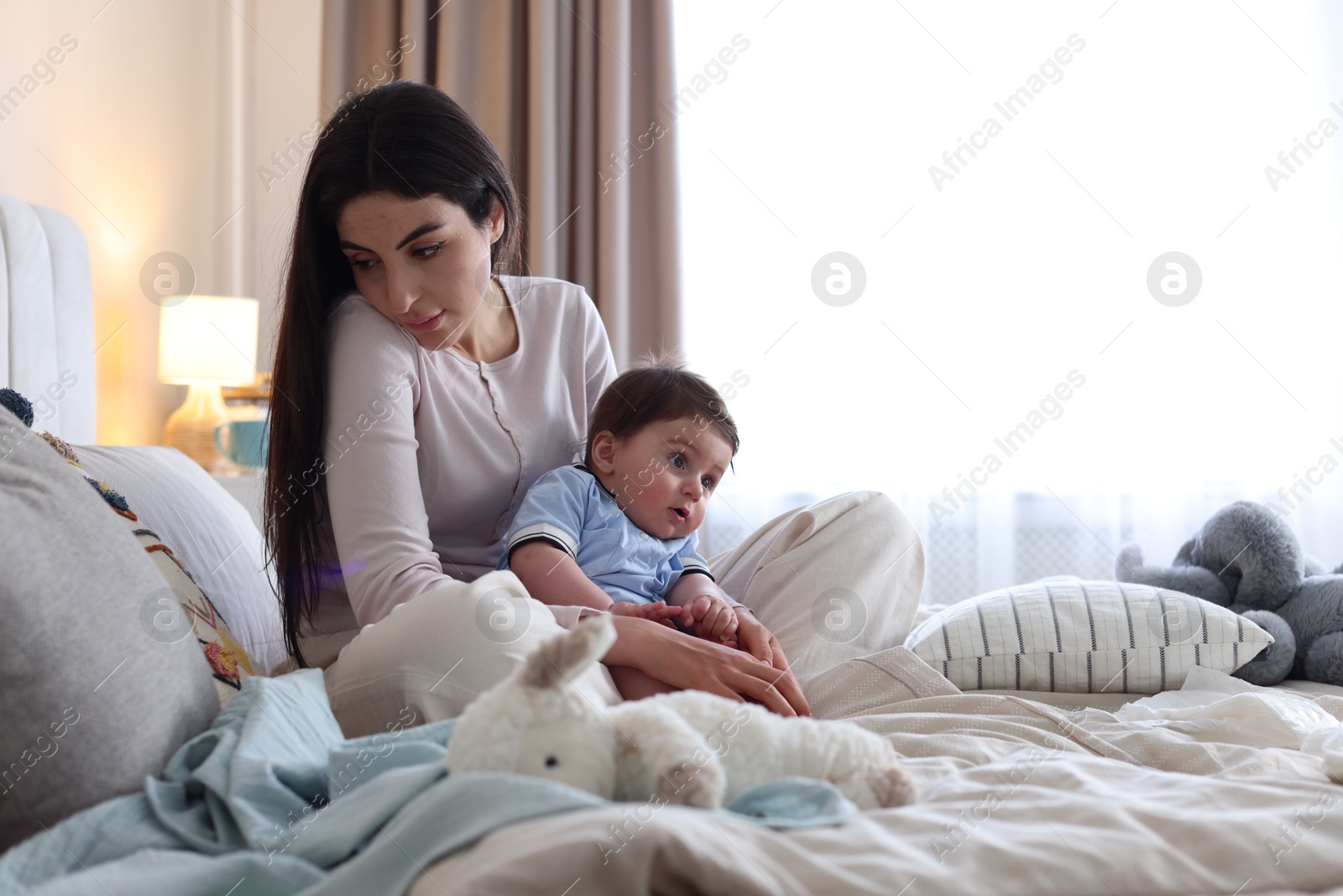 Woman suffering from postpartum depression with her little baby on bed at home. Space for text Photo of Woman suffering from postpartum depression with her little baby on bed at home. Space for text