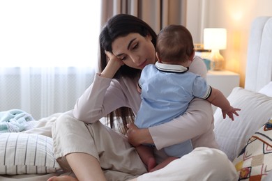 Photo of Woman suffering from postpartum depression with her little baby on bed at home