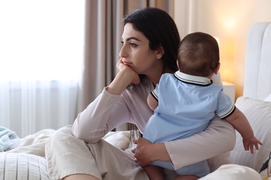 Photo of Woman suffering from postpartum depression with her little baby on bed at home. Space for text