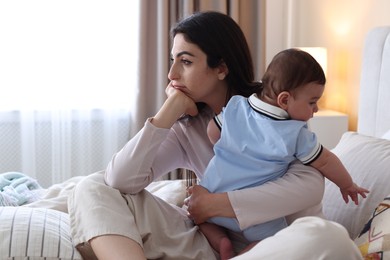 Photo of Woman suffering from postpartum depression with her little baby on bed at home. Space for text
