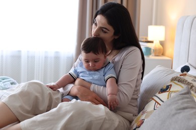 Photo of Woman suffering from postpartum depression with her little baby on bed at home. Space for text