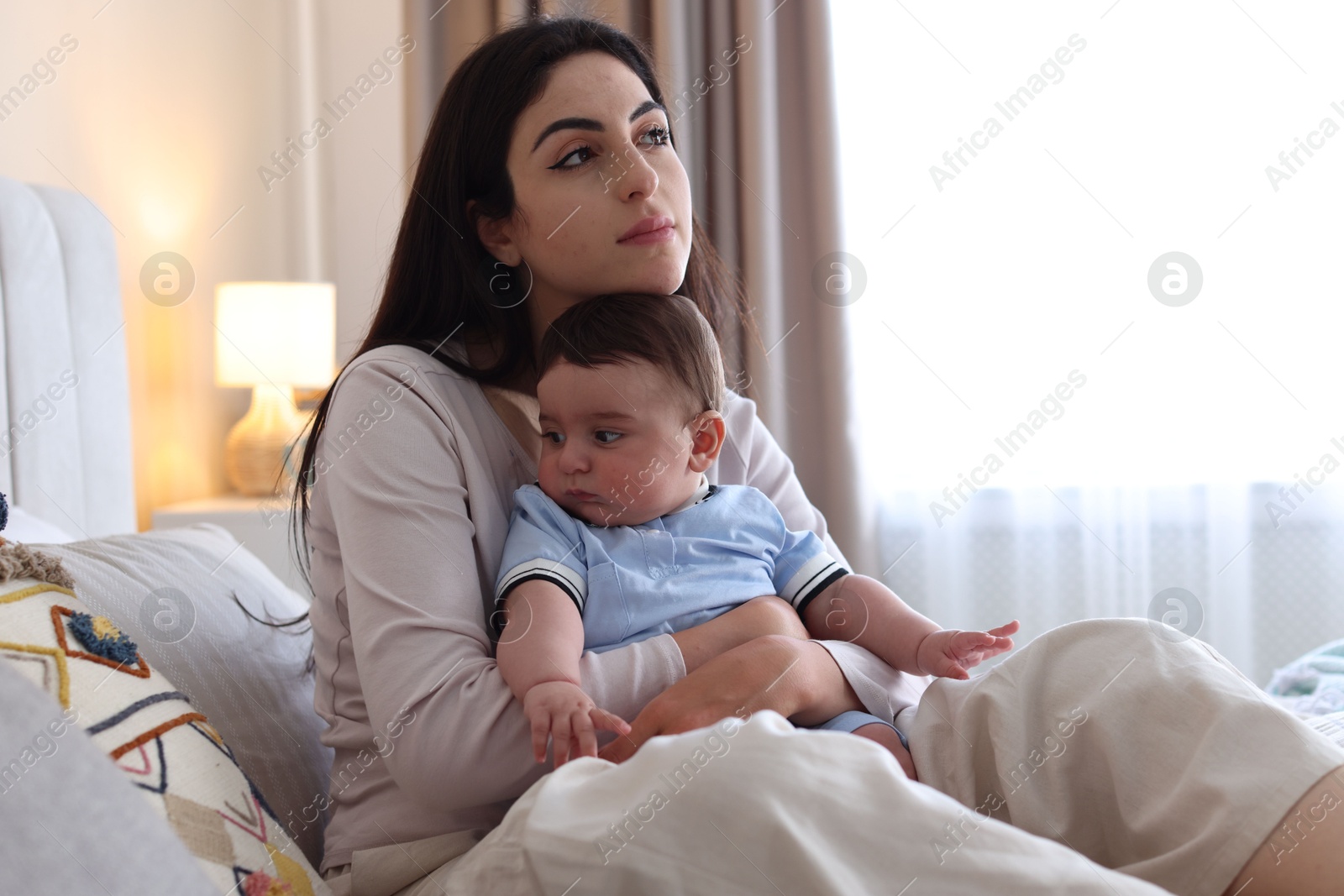 Woman suffering from postpartum depression with her little baby on bed at home. Space for text Photo of Woman suffering from postpartum depression with her little baby on bed at home. Space for text
