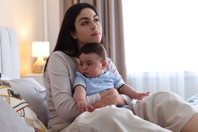 Photo of Woman suffering from postpartum depression with her little baby on bed at home. Space for text