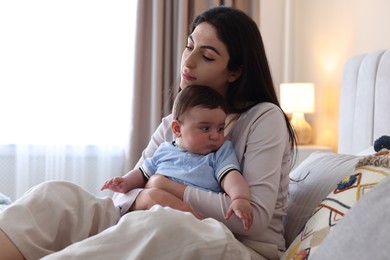 Photo of Woman suffering from postpartum depression with her little baby on bed at home. Space for text