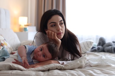 Photo of Woman suffering from postpartum depression with her little baby on bed at home
