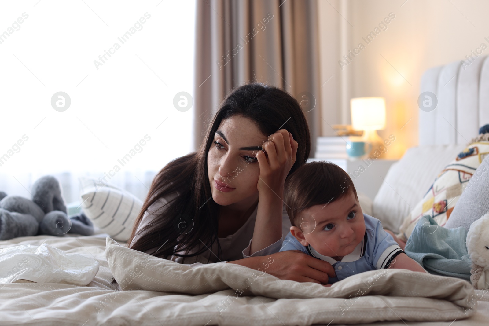 Woman suffering from postpartum depression with her little baby on bed at home. Space for text Photo of Woman suffering from postpartum depression with her little baby on bed at home. Space for text