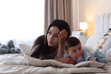 Photo of Woman suffering from postpartum depression with her little baby on bed at home. Space for text