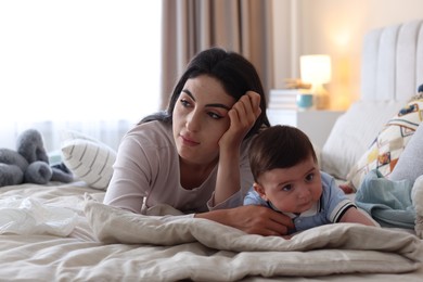 Photo of Woman suffering from postpartum depression with her little baby on bed at home