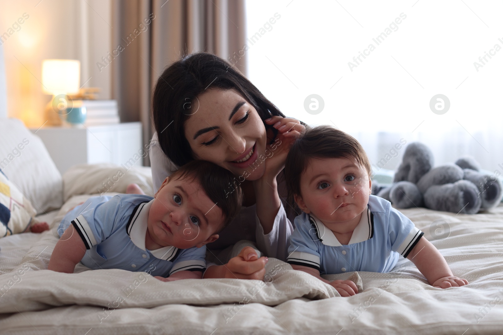 Mother with her cute twin babies on bed at home Photo of Mother with her cute twin babies on bed at home