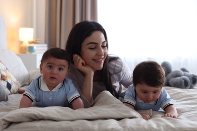 Photo of Mother with her cute twin babies on bed at home