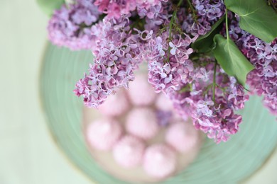 Photo of Beautiful lilac flowers over table with dessert, above view