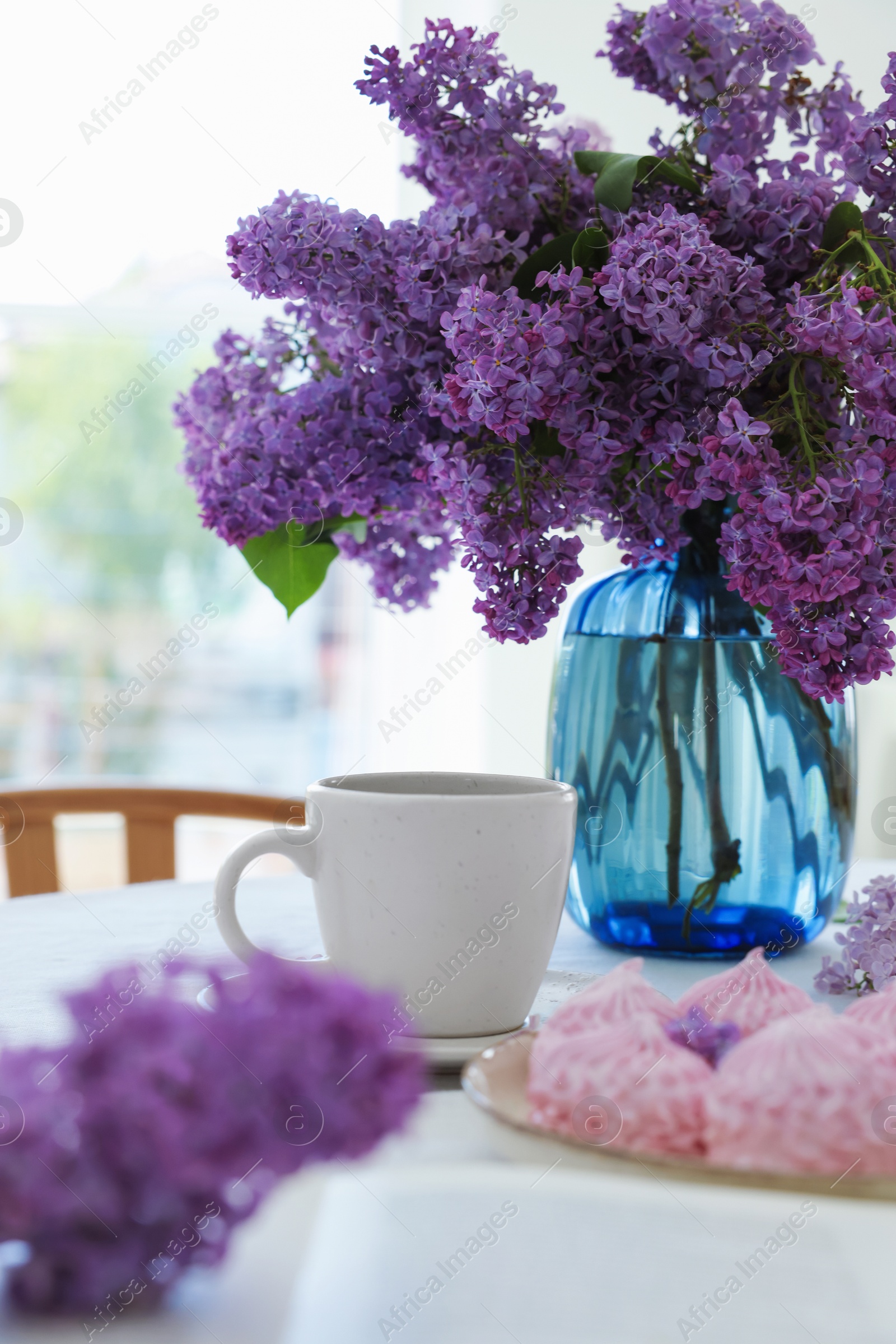 Bouquet of beautiful lilac flowers, coffee and dessert on white table indoors Photo of Bouquet of beautiful lilac flowers, coffee and dessert on white table indoors
