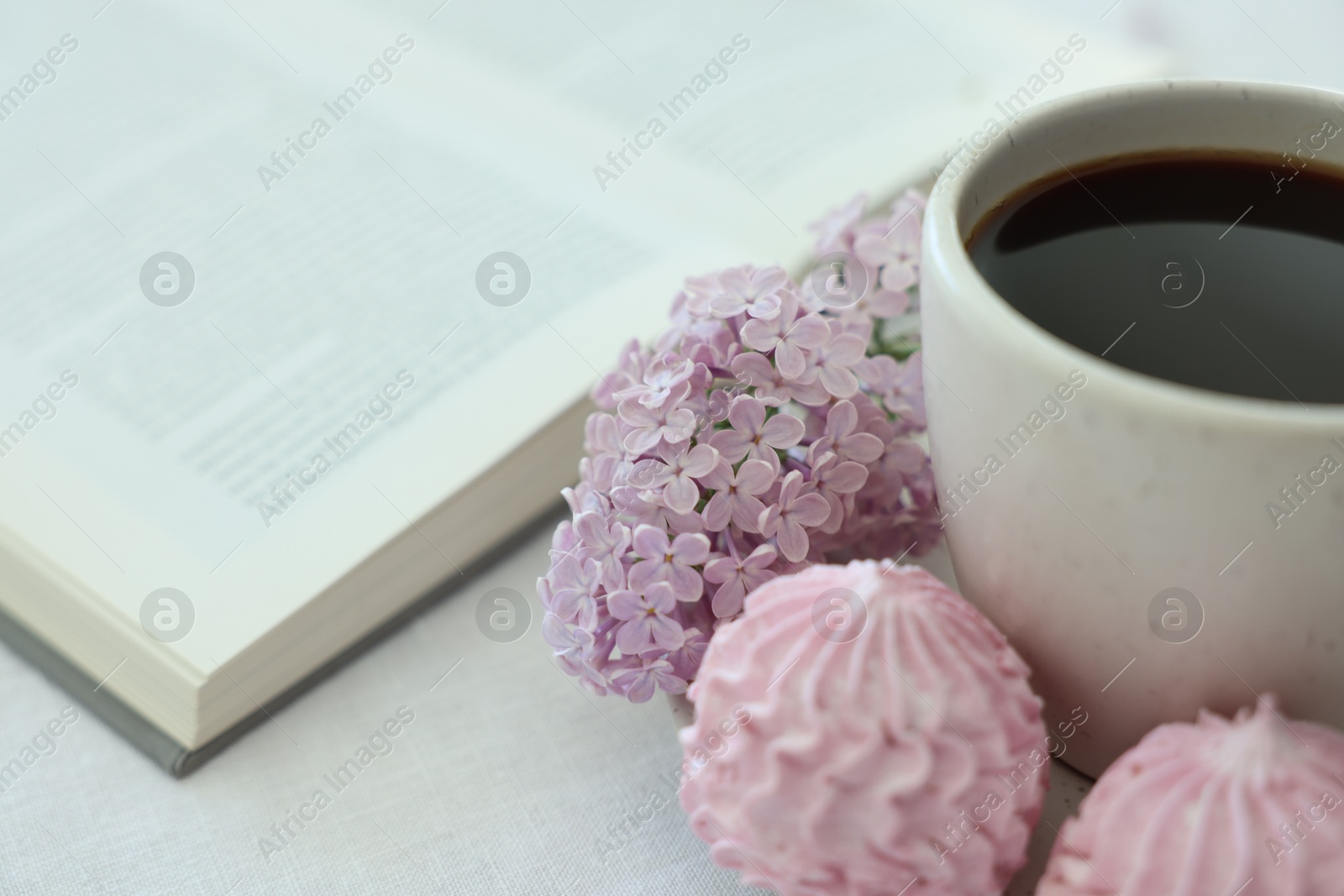 Coffee with dessert, lilac flowers and book on white table, closeup Photo of Coffee with dessert, lilac flowers and book on white table, closeup