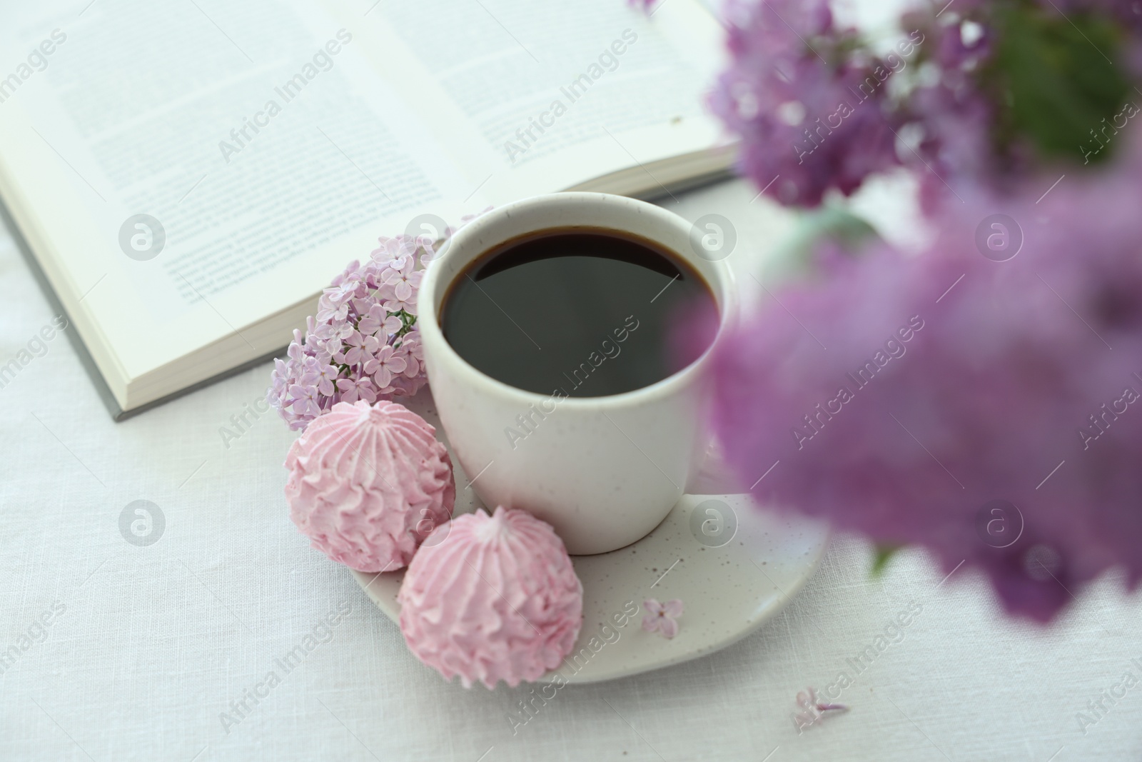 Coffee with dessert, lilac flowers and book on white table, closeup Photo of Coffee with dessert, lilac flowers and book on white table, closeup