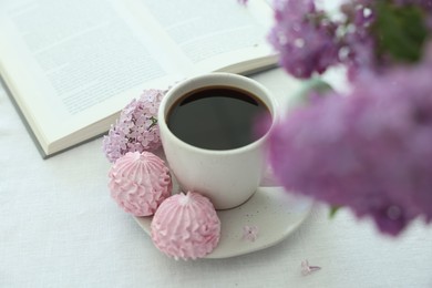 Photo of Coffee with dessert, lilac flowers and book on white table, closeup