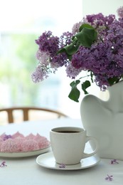 Photo of Bouquet of beautiful lilac flowers, coffee and dessert on white table indoors