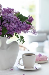 Photo of Bouquet of beautiful lilac flowers, coffee and dessert on white table indoors