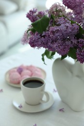 Photo of Bouquet of beautiful lilac flowers, coffee and dessert on white table indoors