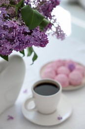 Photo of Bouquet of beautiful lilac flowers, coffee and dessert on white table indoors
