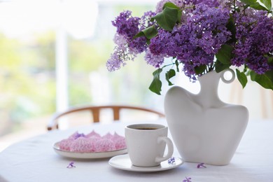 Photo of Bouquet of beautiful lilac flowers, coffee and dessert on white table indoors. Space for text