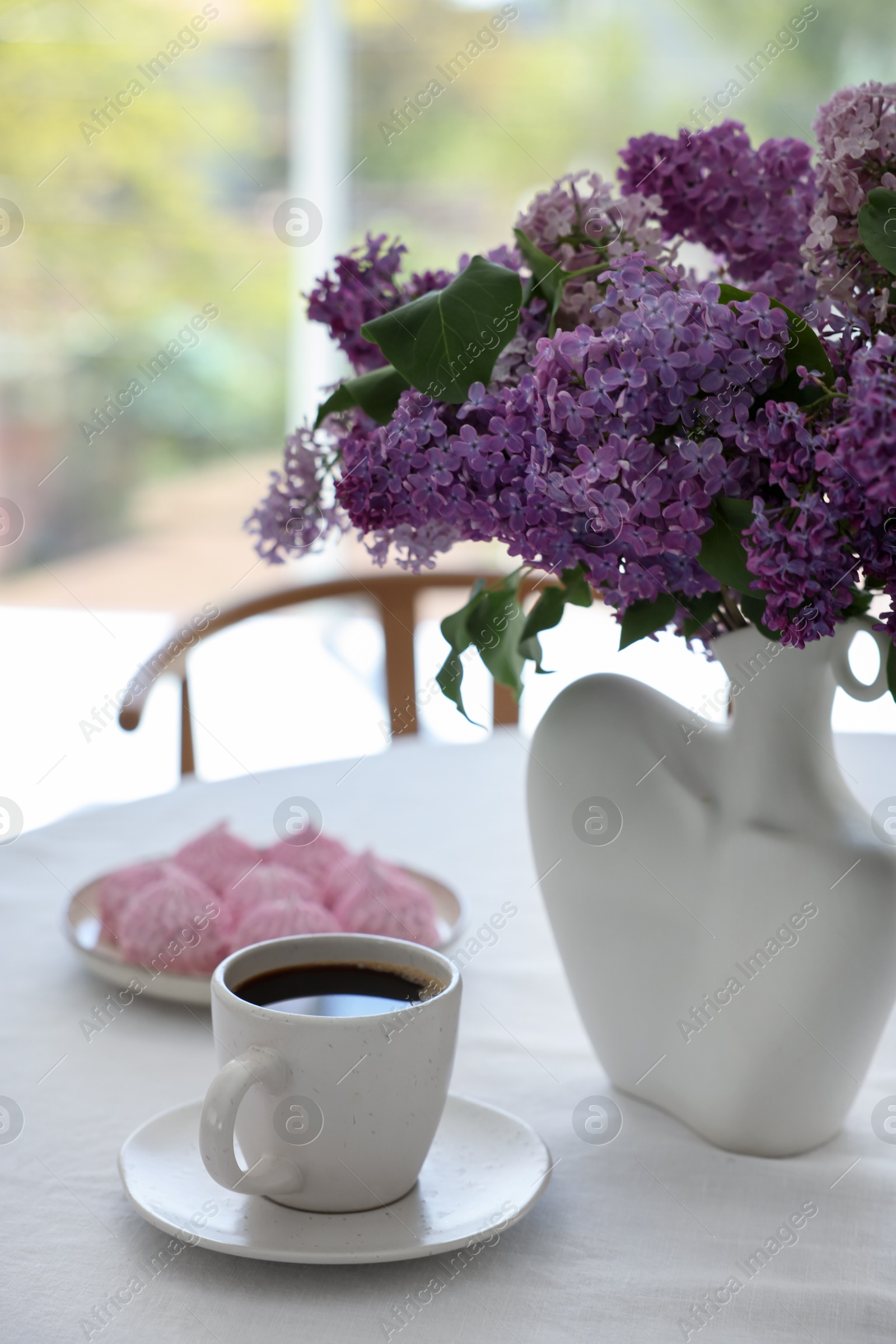 Bouquet of beautiful lilac flowers, coffee and dessert on white table indoors Photo of Bouquet of beautiful lilac flowers, coffee and dessert on white table indoors