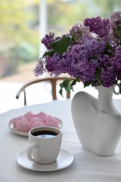 Photo of Bouquet of beautiful lilac flowers, coffee and dessert on white table indoors