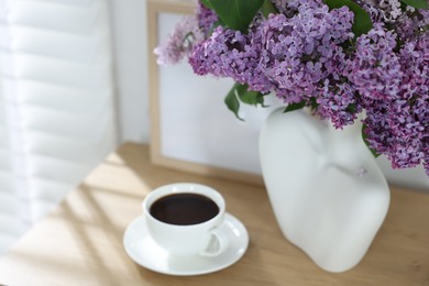 Photo of Bouquet of beautiful lilac flowers and coffee on wooden table