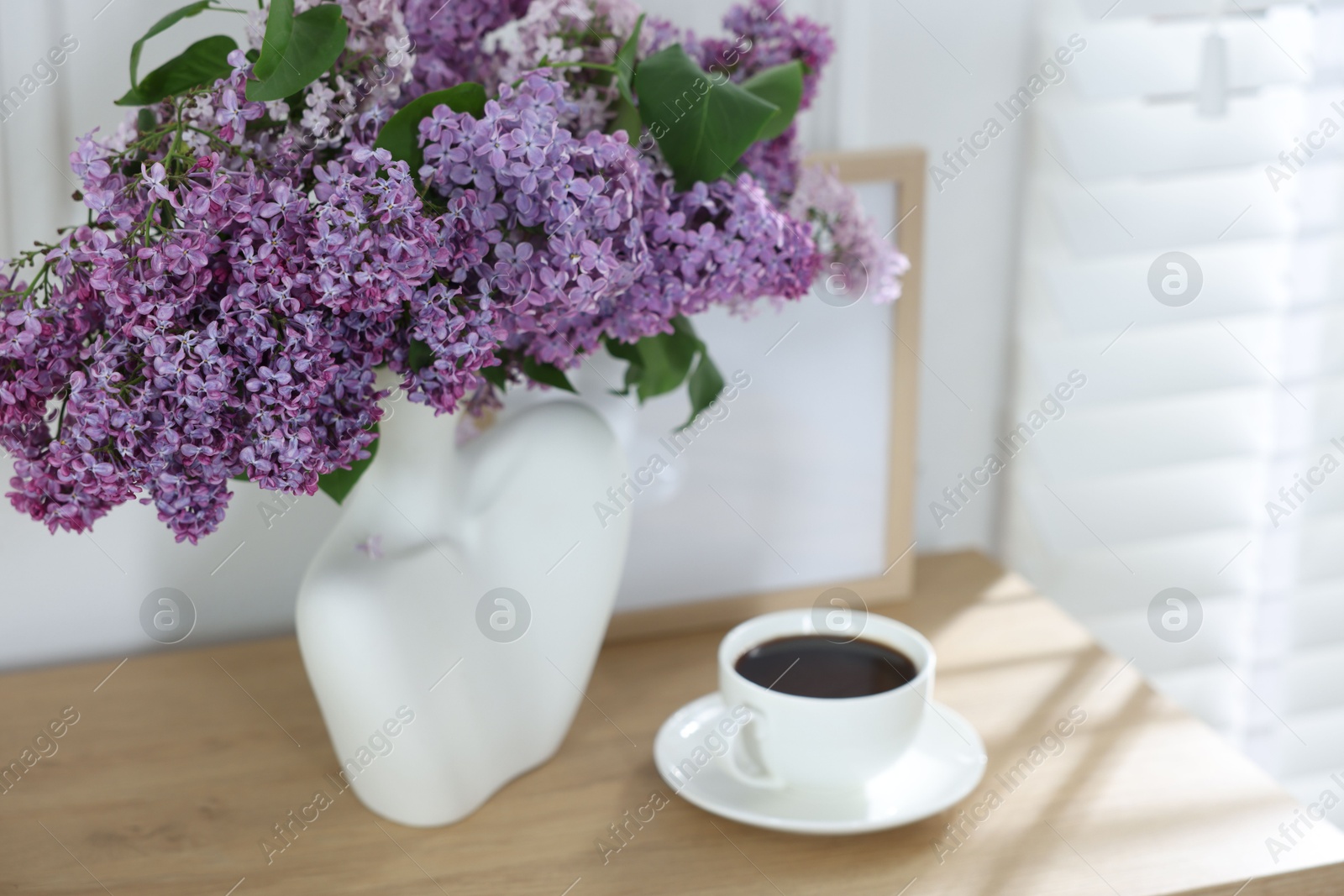Bouquet of beautiful lilac flowers and coffee on wooden table Photo of Bouquet of beautiful lilac flowers and coffee on wooden table