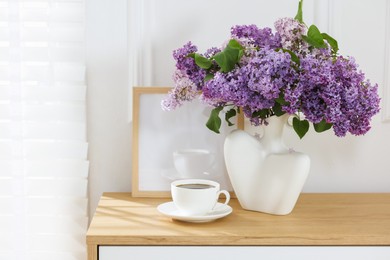 Photo of Bouquet of beautiful lilac flowers and coffee on wooden table. Space for text