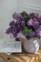 Photo of Bouquet of beautiful lilac flowers and books on wooden table