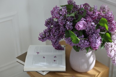 Photo of Bouquet of beautiful lilac flowers and books on wooden table