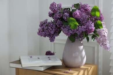 Photo of Bouquet of beautiful lilac flowers and books on wooden table