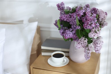 Photo of Bouquet of beautiful lilac flowers, coffee and books on nightstand