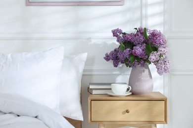 Photo of Bouquet of beautiful lilac flowers, coffee and books on nightstand