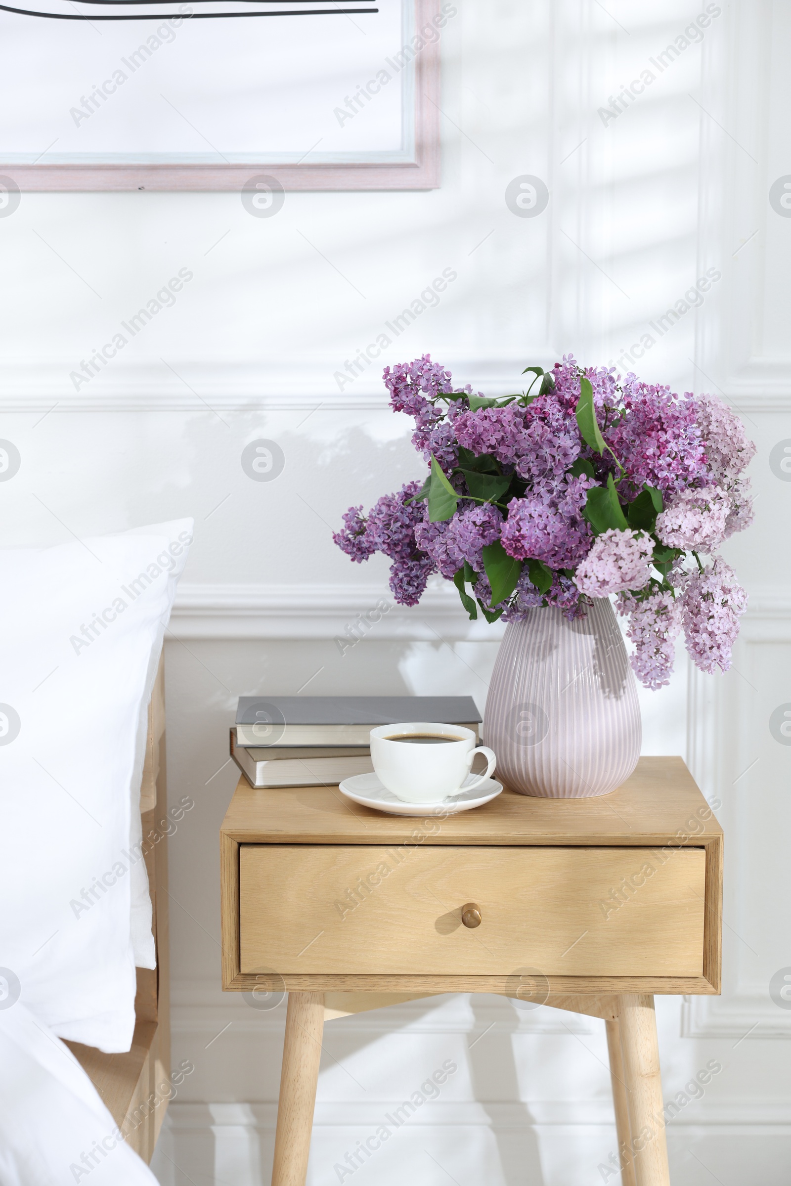 Bouquet of beautiful lilac flowers, coffee and books on nightstand Photo of Bouquet of beautiful lilac flowers, coffee and books on nightstand