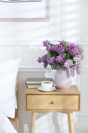 Photo of Bouquet of beautiful lilac flowers, coffee and books on nightstand