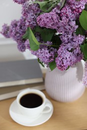 Photo of Bouquet of beautiful lilac flowers and coffee on wooden table, closeup