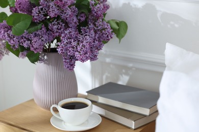 Photo of Bouquet of beautiful lilac flowers, coffee and books on nightstand