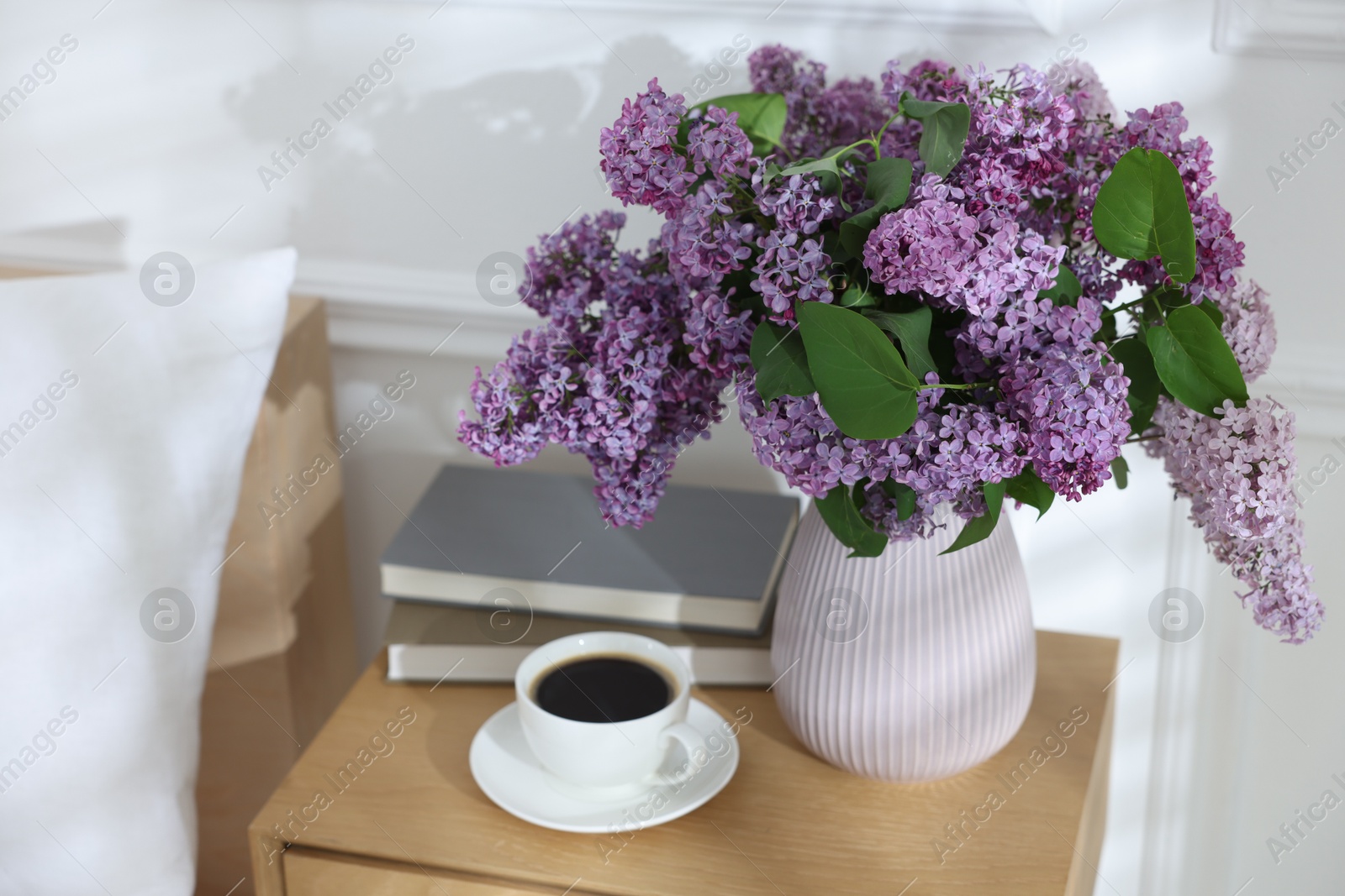 Bouquet of beautiful lilac flowers, coffee and books on nightstand Photo of Bouquet of beautiful lilac flowers, coffee and books on nightstand