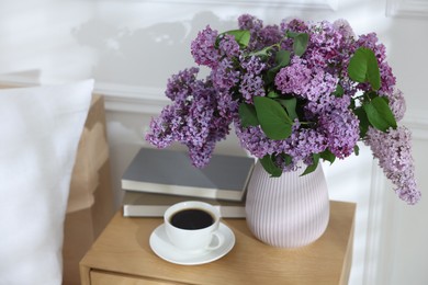 Photo of Bouquet of beautiful lilac flowers, coffee and books on nightstand