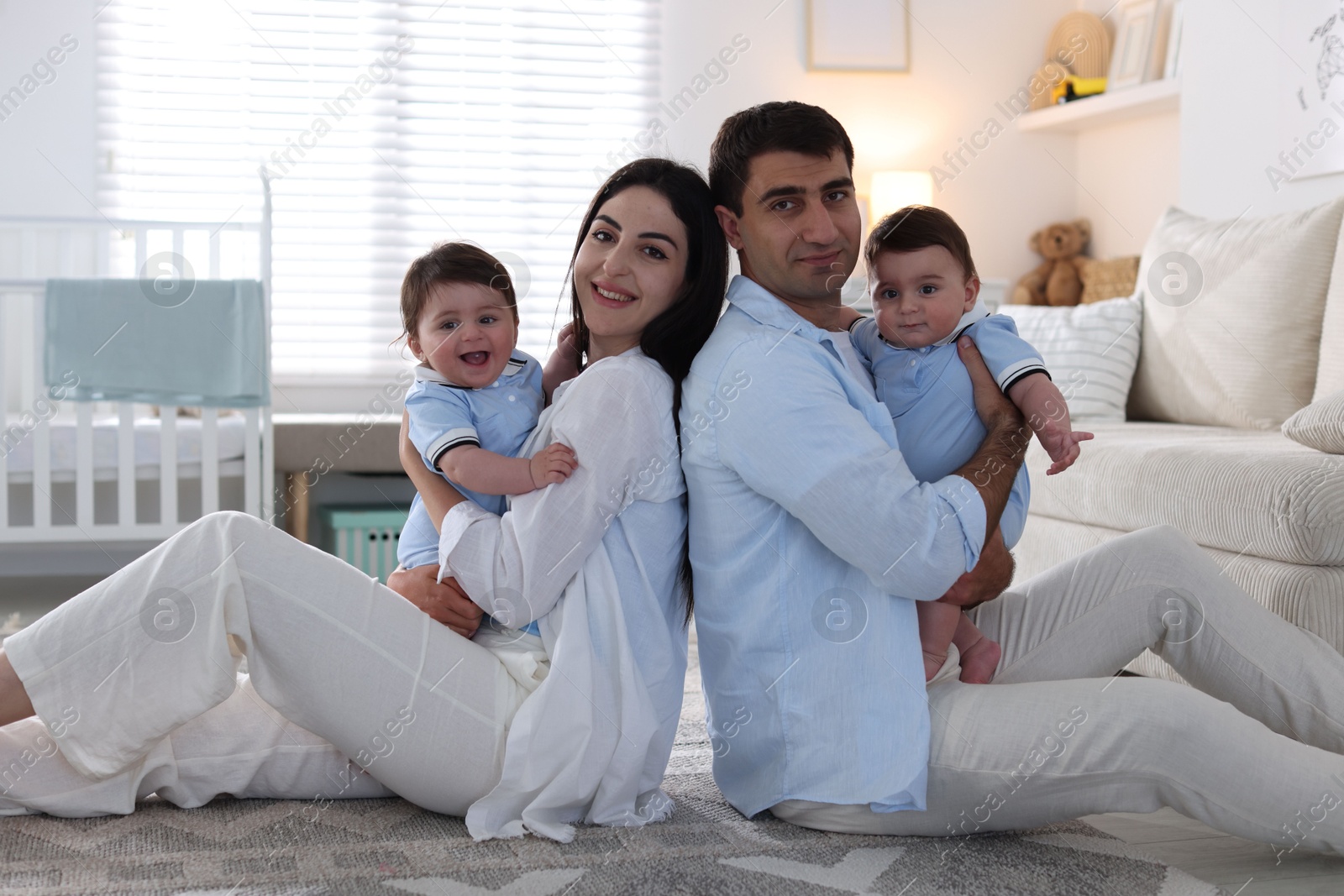 Happy family. Parents with their twin babies at home Photo of Happy family. Parents with their twin babies at home