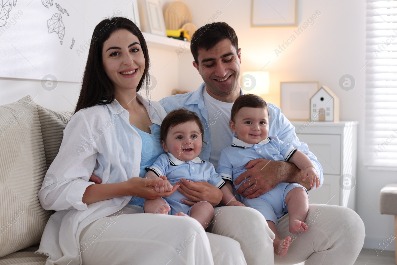 Happy family. Parents with their twin babies on sofa at home Photo of Happy family. Parents with their twin babies on sofa at home
