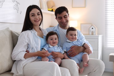 Photo of Happy family. Parents with their twin babies on sofa at home
