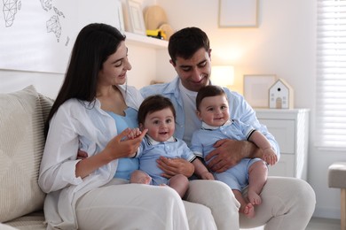 Photo of Happy family. Parents with their twin babies on sofa at home