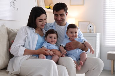 Photo of Happy family. Parents with their twin babies on sofa at home