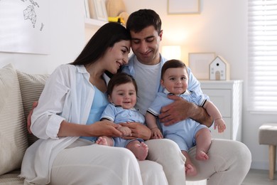 Photo of Happy family. Parents with their twin babies on sofa at home