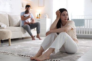 Photo of Woman suffering from postpartum depression and her husband with baby at home, selective focus