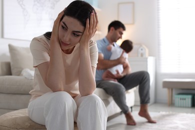 Photo of Woman suffering from postpartum depression and her husband with baby at home, selective focus